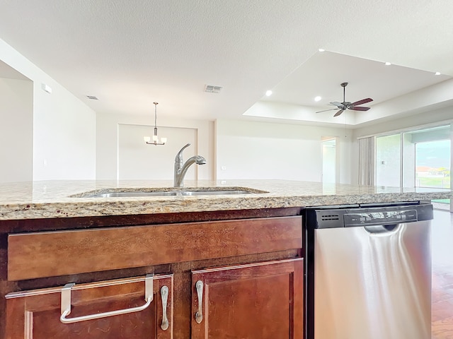 kitchen with ceiling fan, sink, a raised ceiling, stainless steel dishwasher, and decorative light fixtures