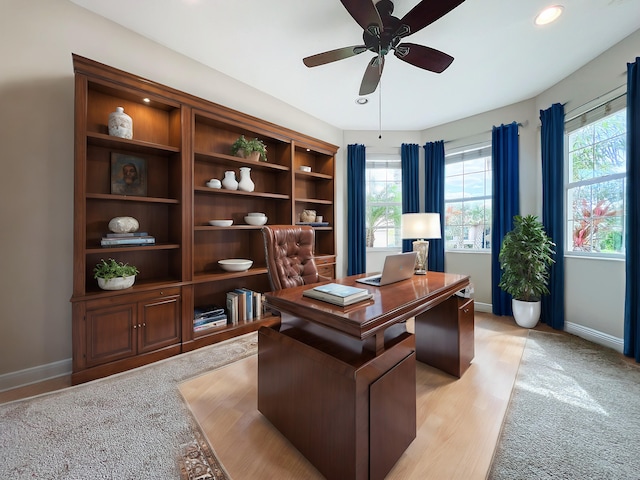 home office with light hardwood / wood-style floors and ceiling fan