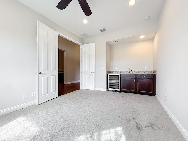 bar with light carpet, wine cooler, and ceiling fan