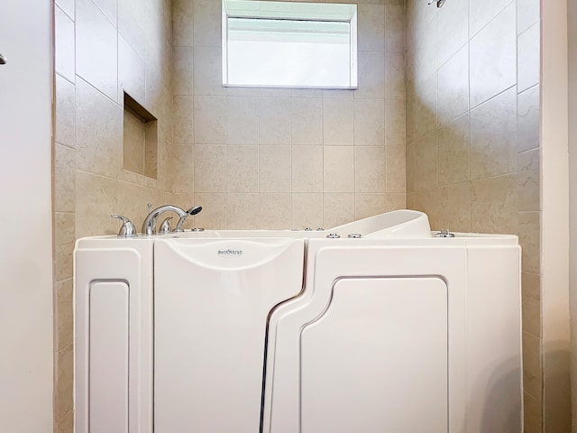 bathroom with a washtub and tile walls