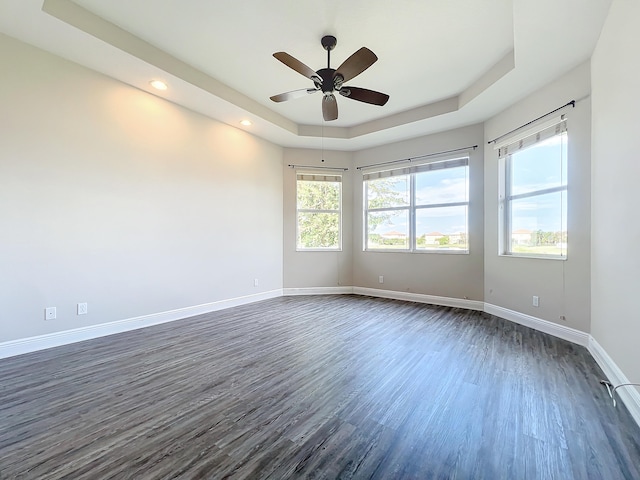 unfurnished room featuring a tray ceiling, ceiling fan, and dark hardwood / wood-style floors