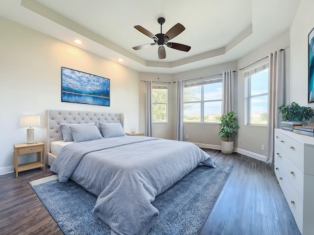 bedroom with a tray ceiling, ceiling fan, and dark hardwood / wood-style floors