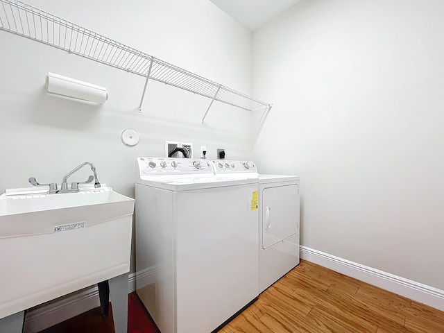 laundry area with light hardwood / wood-style floors, washing machine and dryer, and sink