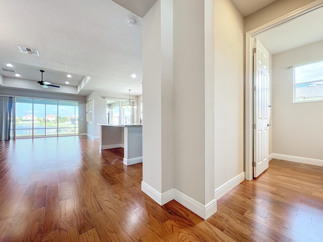 corridor featuring light hardwood / wood-style flooring and a textured ceiling