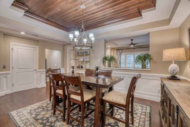 dining space featuring a chandelier, a tray ceiling, crown molding, and dark wood-type flooring