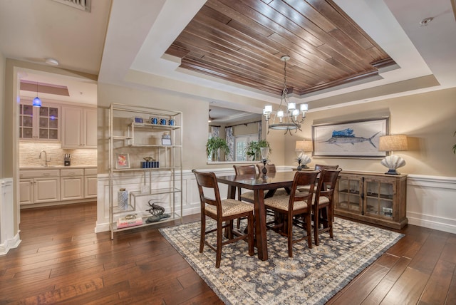 dining area featuring dark hardwood / wood-style flooring, a raised ceiling, a notable chandelier, and sink