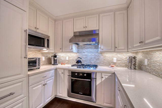 kitchen featuring white cabinets, stainless steel appliances, and tasteful backsplash