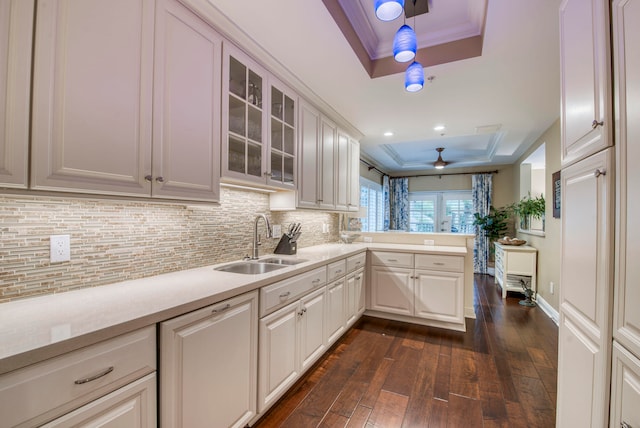 kitchen with sink, a raised ceiling, dark hardwood / wood-style flooring, kitchen peninsula, and white cabinets