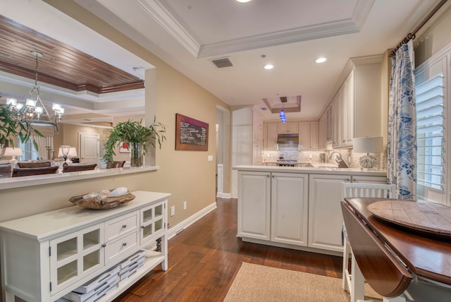 kitchen with a tray ceiling, white cabinetry, hanging light fixtures, and dark wood-type flooring