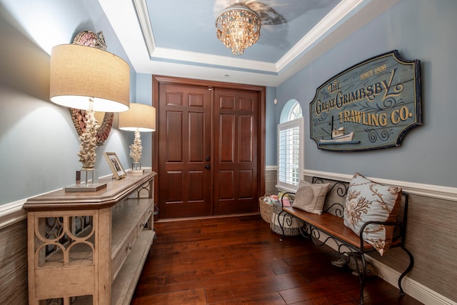 entrance foyer featuring ornamental molding, dark hardwood / wood-style flooring, a tray ceiling, and a notable chandelier