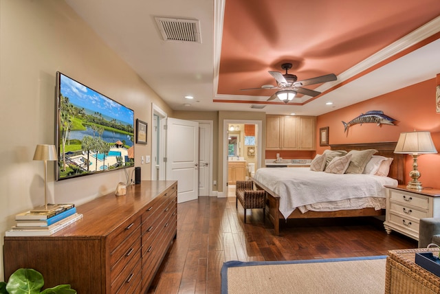 bedroom featuring a raised ceiling, ensuite bath, ceiling fan, and dark wood-type flooring