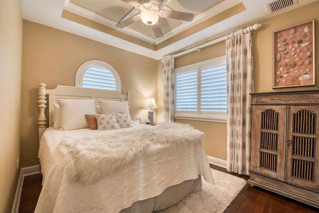 bedroom with multiple windows, a raised ceiling, ceiling fan, and dark wood-type flooring