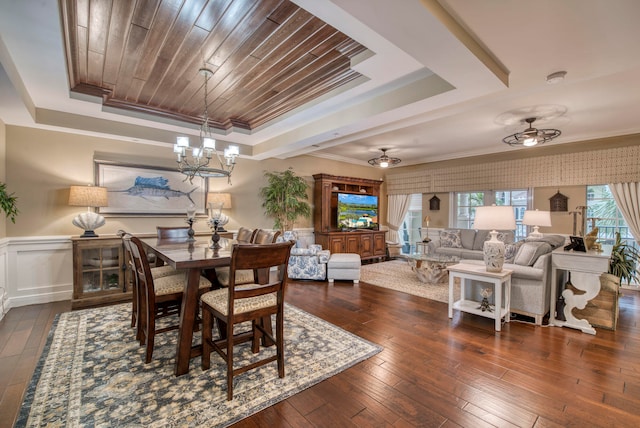 dining area with dark hardwood / wood-style floors, crown molding, ceiling fan with notable chandelier, and a tray ceiling