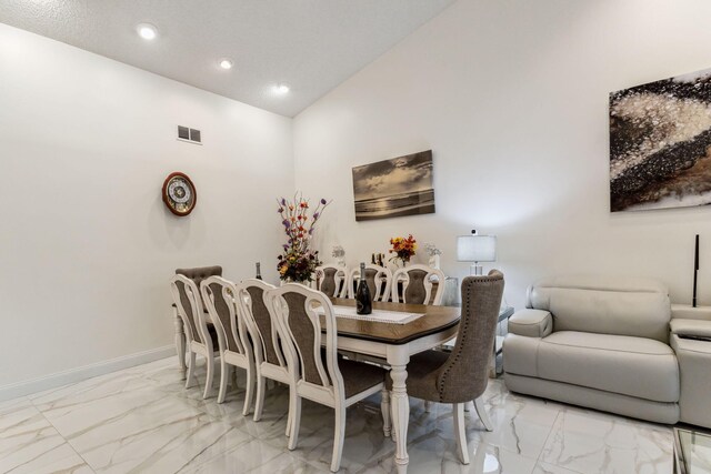 dining space featuring high vaulted ceiling