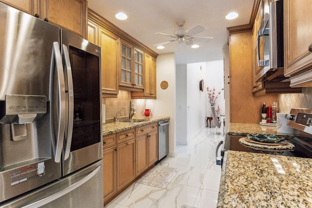 kitchen featuring ceiling fan, light stone counters, backsplash, and appliances with stainless steel finishes