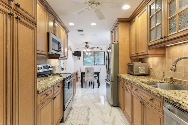 kitchen with light stone counters, sink, decorative backsplash, and stainless steel appliances