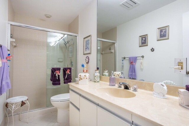 bathroom with tile patterned floors, vanity, a shower with shower door, and toilet