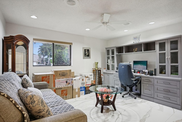 office space featuring ceiling fan, built in desk, and a textured ceiling