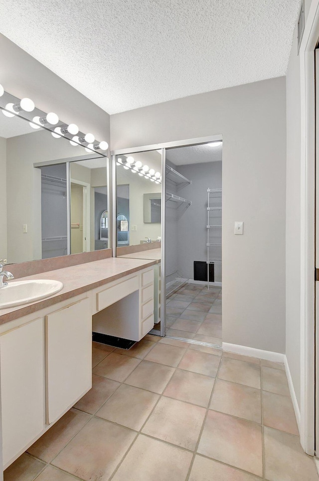 bathroom with tile patterned flooring, vanity, and a textured ceiling