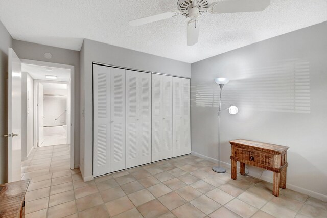 tiled bedroom with ceiling fan, a closet, and a textured ceiling