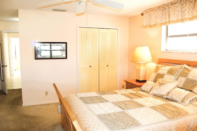 carpeted bedroom featuring ceiling fan, a closet, and a textured ceiling