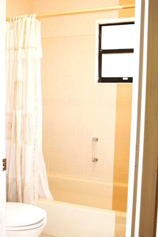 bathroom featuring shower / tub combo and toilet