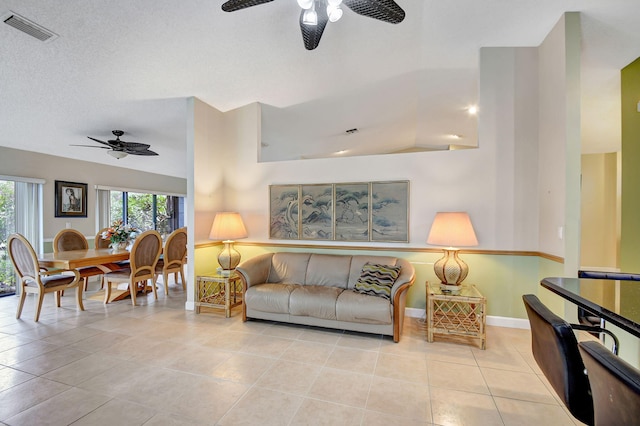 tiled living room featuring a textured ceiling, ceiling fan, and lofted ceiling