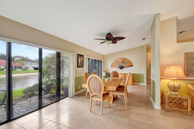 tiled dining space with a water view and ceiling fan