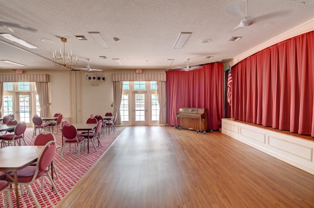 miscellaneous room featuring hardwood / wood-style flooring, ceiling fan with notable chandelier, and a textured ceiling