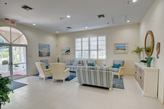 tiled living room with french doors and a textured ceiling