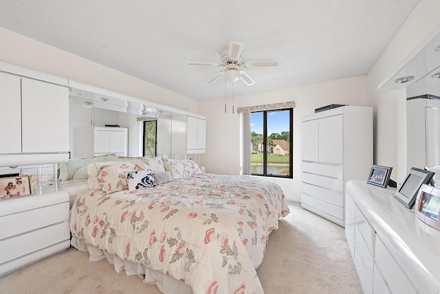 carpeted bedroom with ceiling fan and a textured ceiling