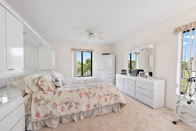 bedroom featuring a textured ceiling, ceiling fan, independent washer and dryer, and light carpet