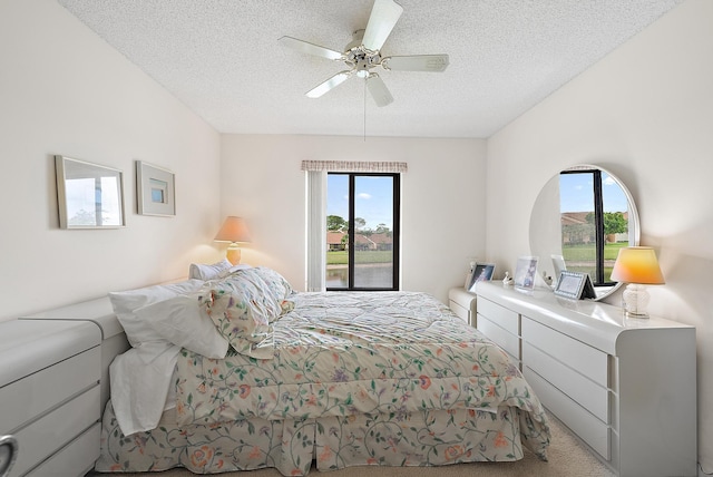 bedroom featuring a textured ceiling, ceiling fan, light carpet, and multiple windows