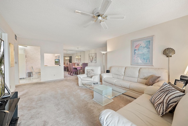 carpeted living room with ceiling fan with notable chandelier and a textured ceiling