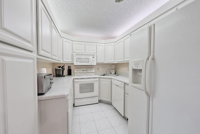 kitchen with white appliances, white cabinets, sink, light tile patterned floors, and a textured ceiling