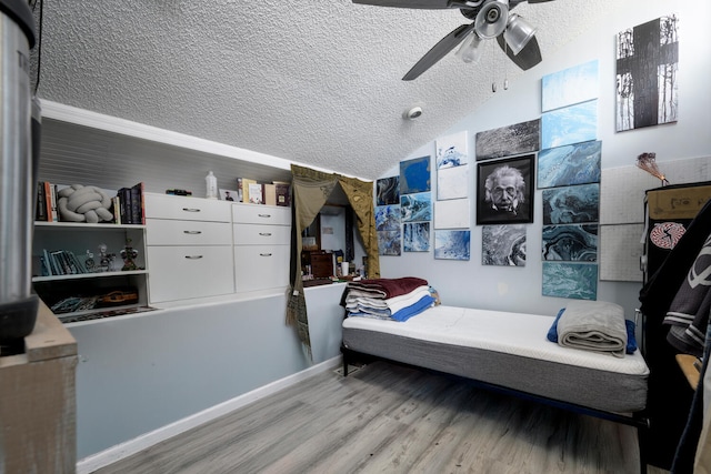 bedroom with a textured ceiling, light hardwood / wood-style floors, ceiling fan, and lofted ceiling