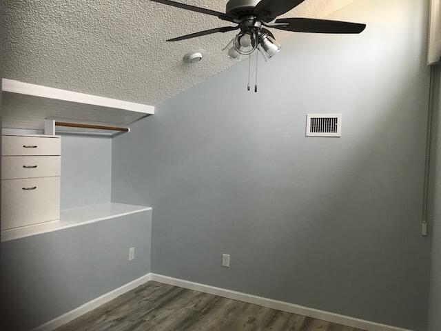 unfurnished room featuring ceiling fan, dark hardwood / wood-style flooring, and a textured ceiling