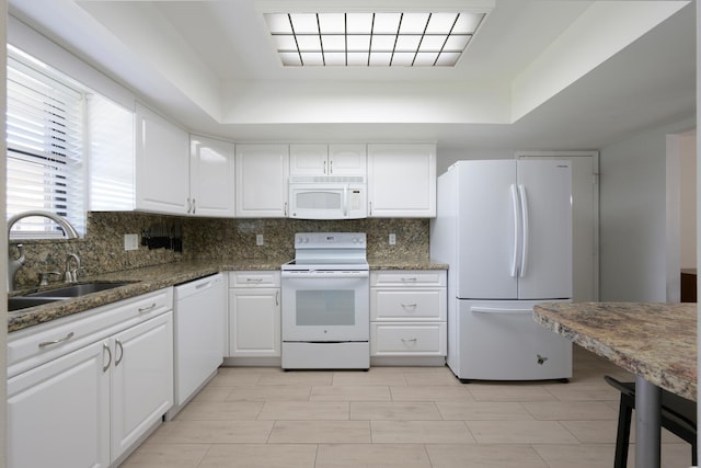 kitchen with sink, dark stone counters, white appliances, decorative backsplash, and white cabinets