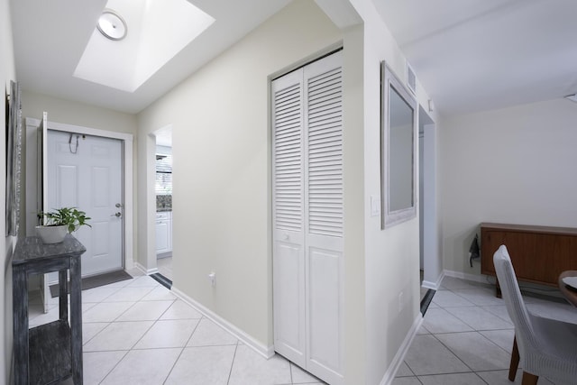 foyer entrance with a skylight and light tile patterned flooring