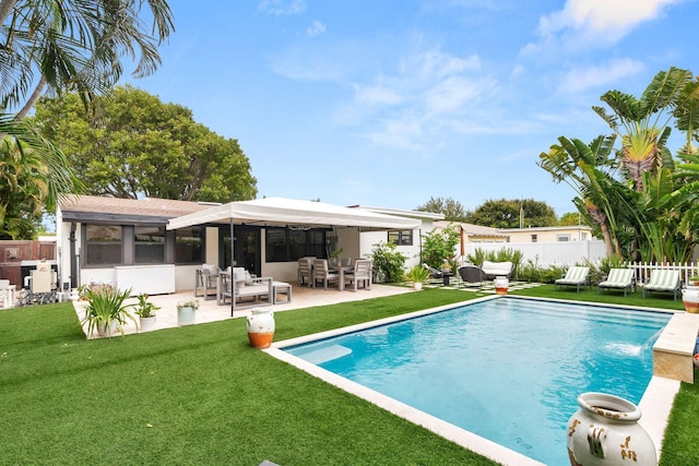 rear view of property featuring a sunroom, a fenced in pool, a patio, and a lawn