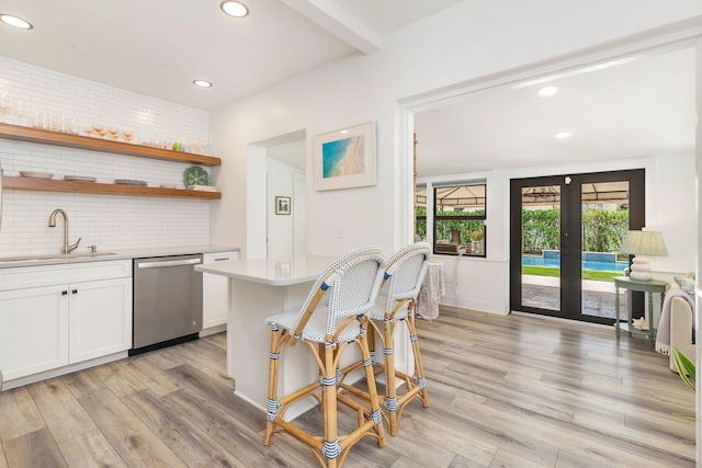 kitchen with dishwasher, french doors, a kitchen breakfast bar, sink, and white cabinetry