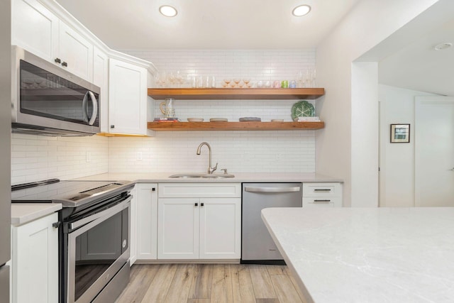 kitchen with white cabinetry, sink, light hardwood / wood-style flooring, and appliances with stainless steel finishes