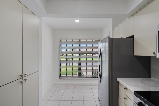 kitchen featuring white cabinets, light stone countertops, and light tile patterned floors