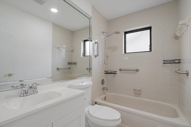 full bathroom featuring vanity, tiled shower / bath, and toilet