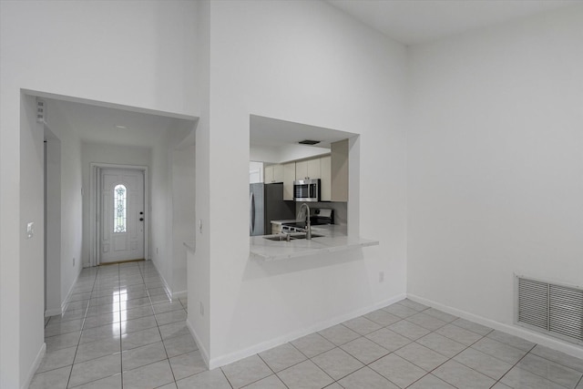 foyer entrance with light tile patterned floors, a towering ceiling, and sink