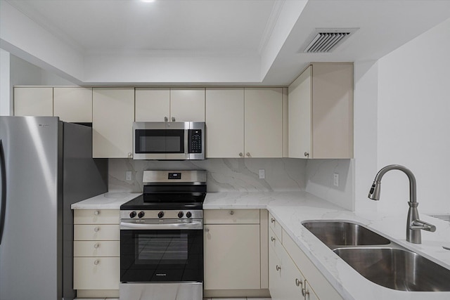 kitchen featuring sink, stainless steel appliances, backsplash, crown molding, and cream cabinetry