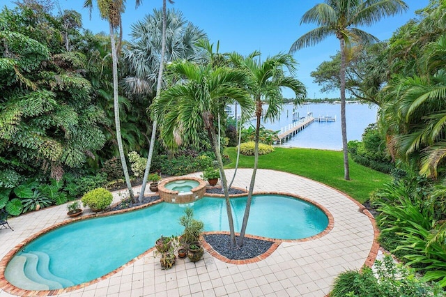 view of pool featuring an in ground hot tub, a yard, a water view, and a dock