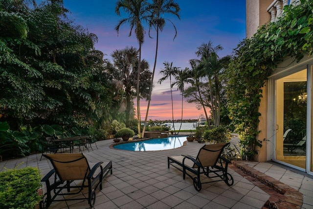 pool at dusk featuring a patio area