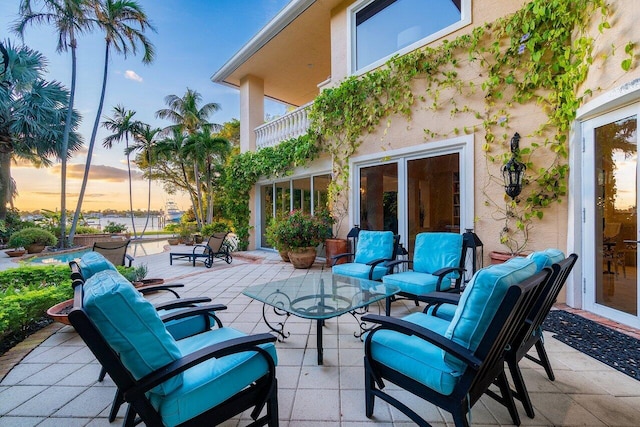 patio terrace at dusk with an outdoor living space and a balcony