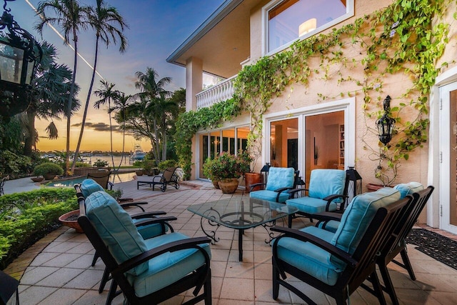 patio terrace at dusk featuring outdoor lounge area and a balcony